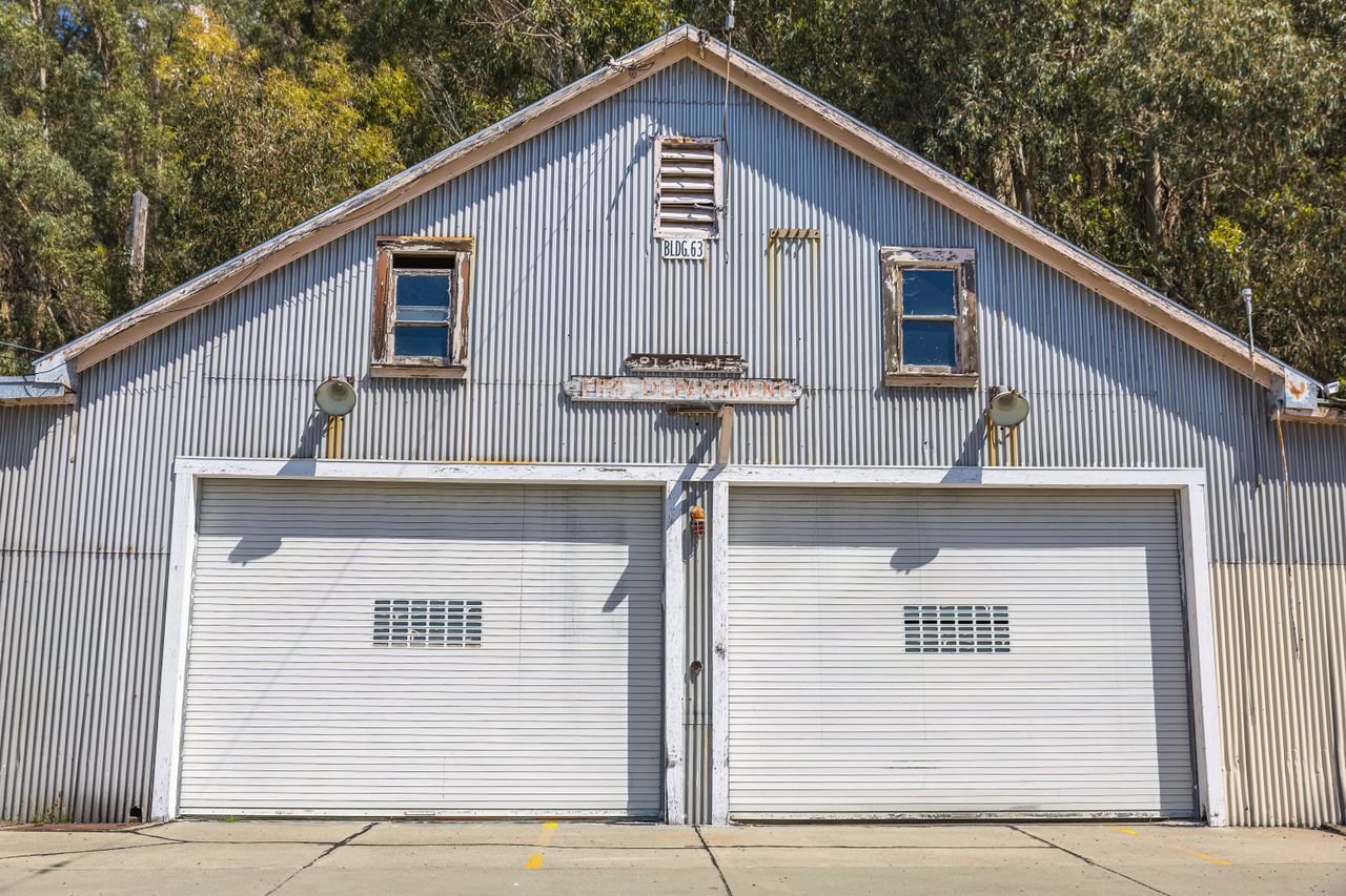 Mastering the First Impression: Your intriguing post title goes here A sunlit vintage metal garage with double doors and rustic charm amidst trees.